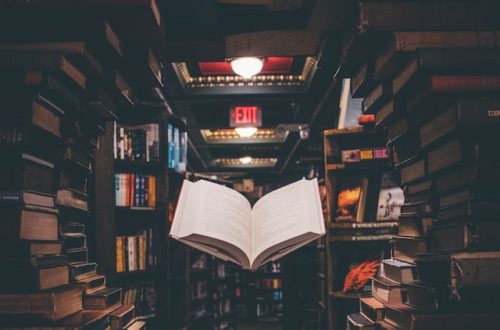 creative writing - a book floats infront of library stacks of books